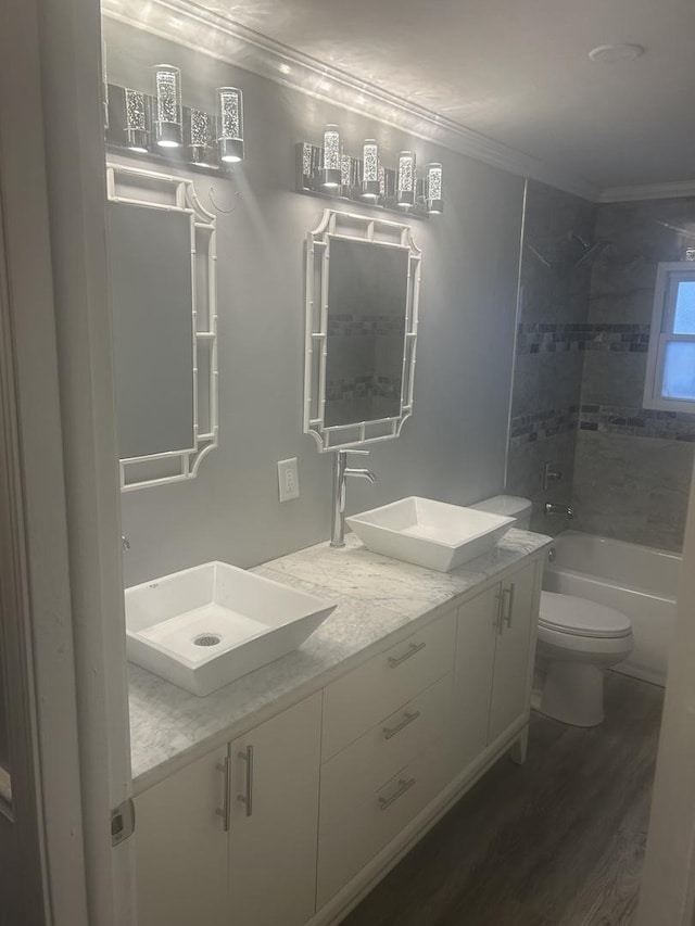 full bathroom with crown molding, hardwood / wood-style flooring, tiled shower / bath combo, vanity, and toilet