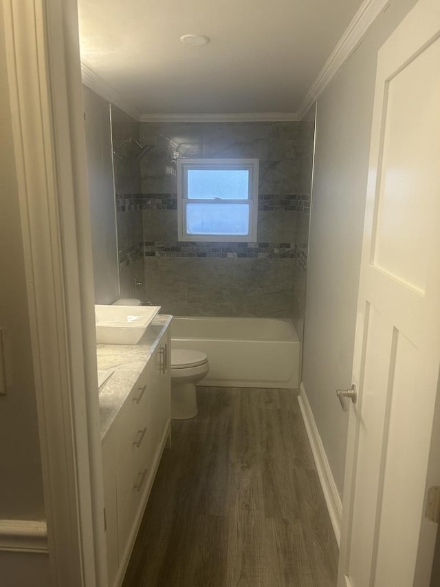 full bathroom with vanity, wood-type flooring, ornamental molding, toilet, and tiled shower / bath