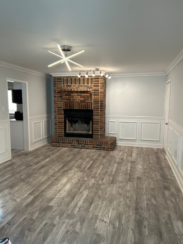 unfurnished living room with crown molding, a fireplace, wood-type flooring, and rail lighting