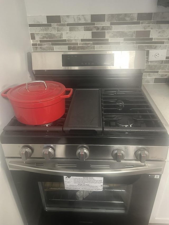 interior details with stainless steel range with gas stovetop and decorative backsplash