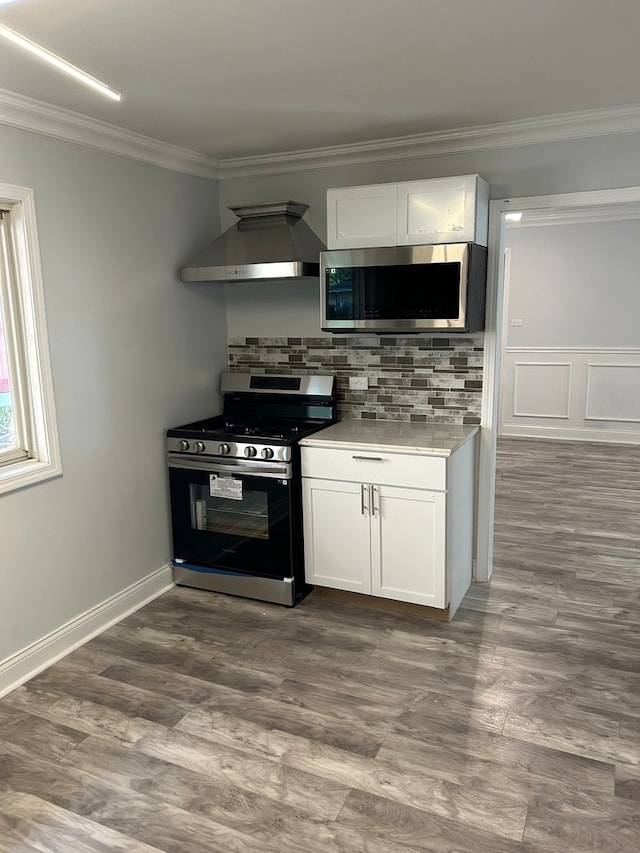 kitchen with appliances with stainless steel finishes, white cabinets, extractor fan, and dark hardwood / wood-style flooring