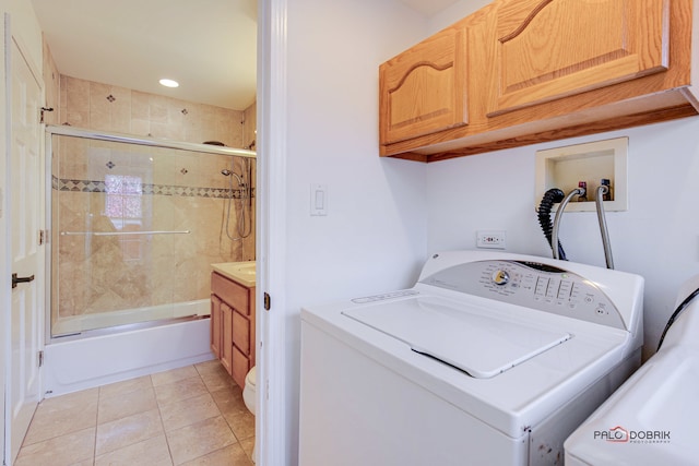 laundry area with washer / dryer, light tile patterned floors, and cabinets