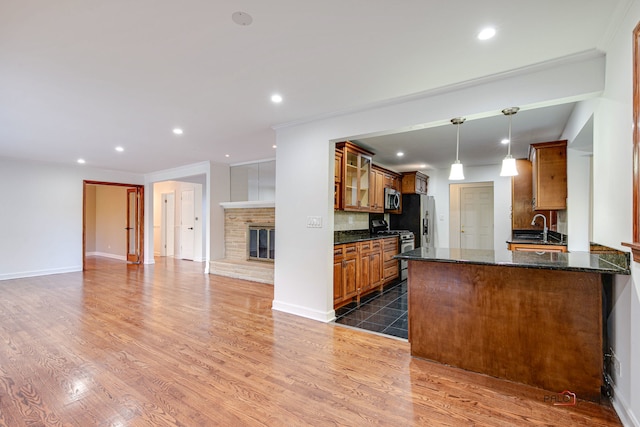 kitchen with decorative backsplash, dark hardwood / wood-style floors, hanging light fixtures, stainless steel appliances, and dark stone counters