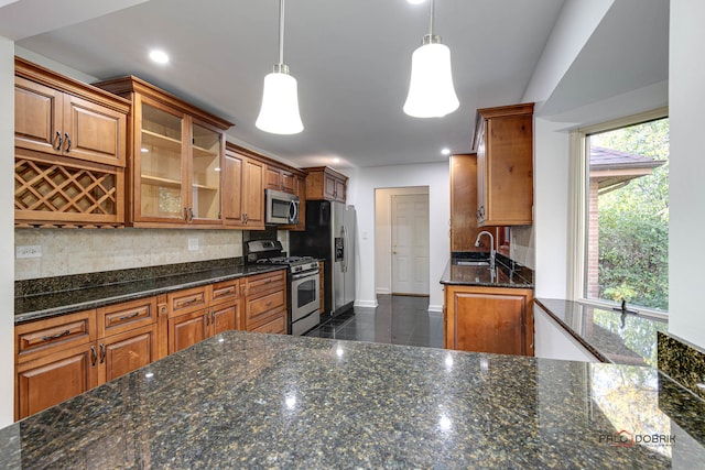 kitchen featuring backsplash, stainless steel appliances, decorative light fixtures, and dark stone counters