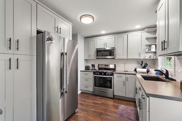 kitchen featuring decorative backsplash, sink, white cabinetry, appliances with stainless steel finishes, and dark hardwood / wood-style flooring