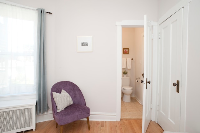 bathroom with radiator heating unit, hardwood / wood-style floors, and toilet