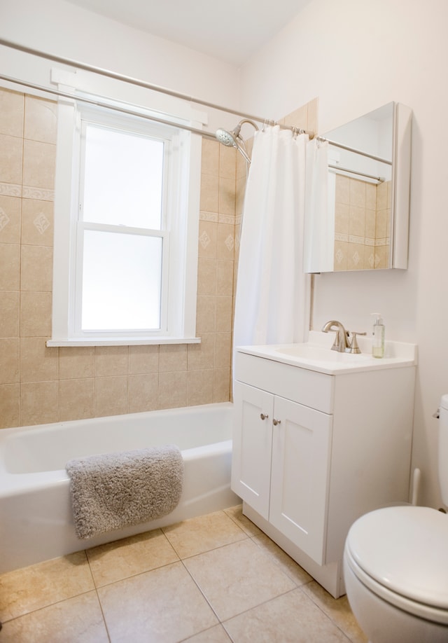 full bathroom with tile patterned flooring, shower / bath combination with curtain, vanity, and toilet