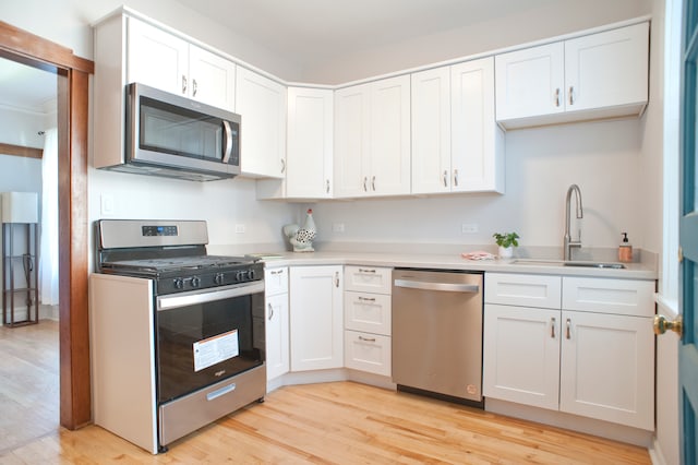 kitchen featuring sink, white cabinetry, stainless steel appliances, and light hardwood / wood-style flooring