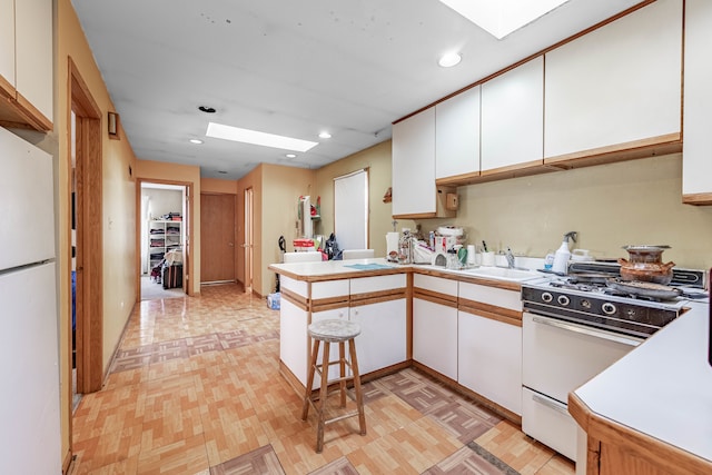 kitchen with a kitchen bar, white cabinets, kitchen peninsula, and white appliances