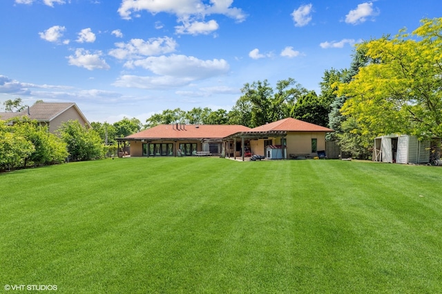 back of property with a storage unit and a yard