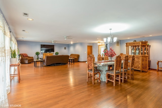 dining area featuring light hardwood / wood-style flooring and ceiling fan with notable chandelier