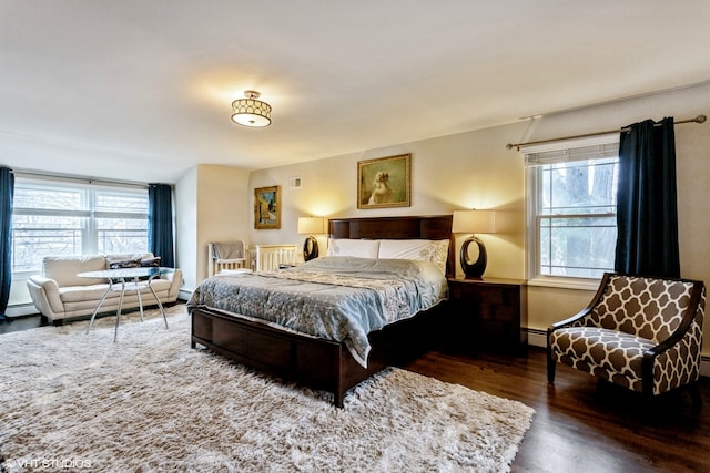 bedroom featuring baseboard heating and dark hardwood / wood-style floors