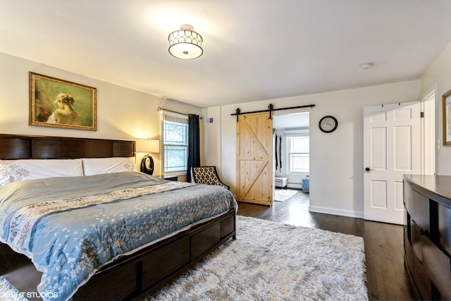 bedroom featuring multiple windows, a barn door, and dark hardwood / wood-style flooring