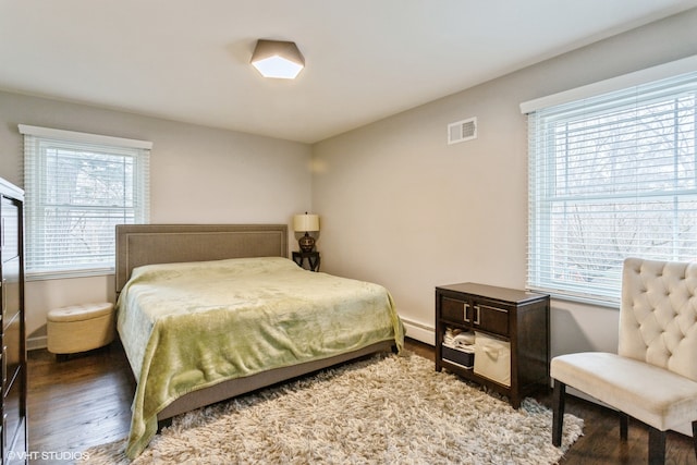 bedroom featuring multiple windows, baseboard heating, and hardwood / wood-style floors