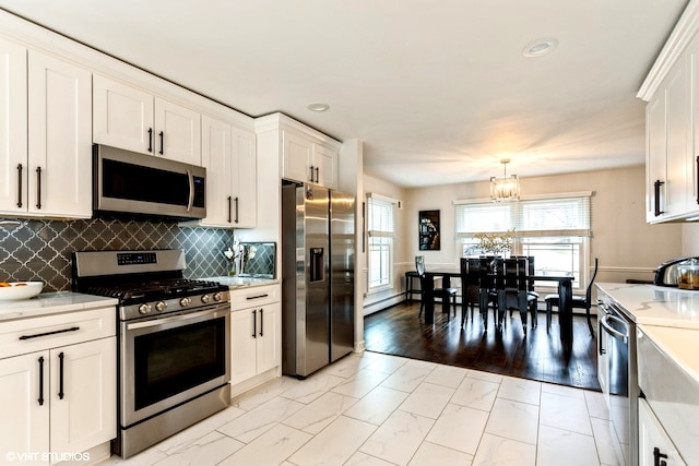 kitchen with white cabinetry, light hardwood / wood-style floors, stainless steel appliances, decorative light fixtures, and an inviting chandelier