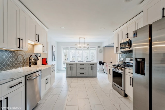 kitchen featuring stainless steel appliances, decorative light fixtures, and white cabinets