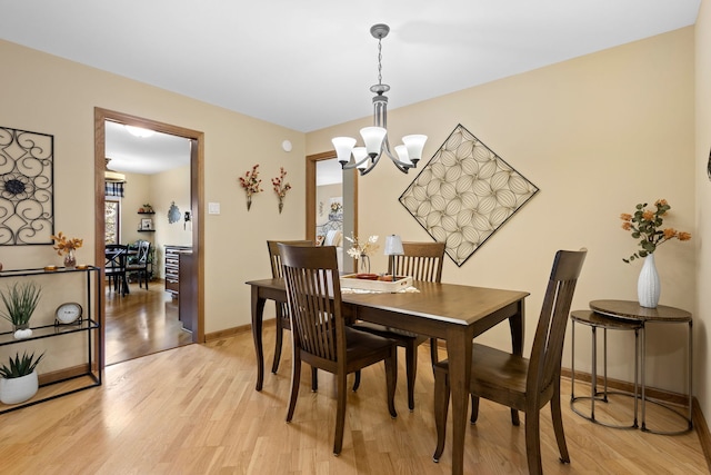 dining area with light hardwood / wood-style floors and a notable chandelier