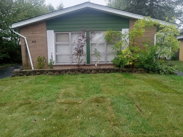 exterior space with brick siding and a front lawn