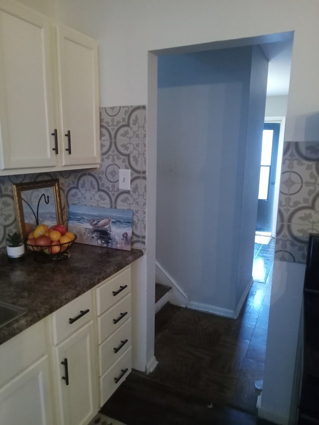 kitchen with dark parquet flooring and white cabinets