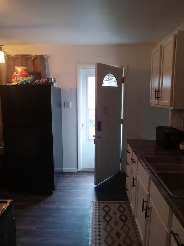 kitchen with black fridge, sink, white cabinets, and dark hardwood / wood-style floors