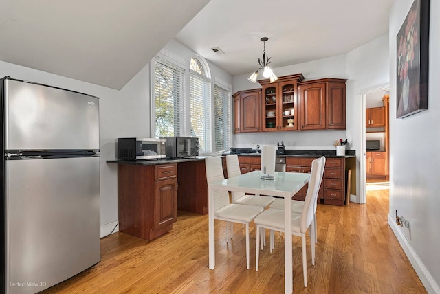 kitchen with appliances with stainless steel finishes, light hardwood / wood-style flooring, and hanging light fixtures