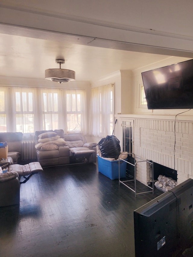 living room with a healthy amount of sunlight, dark hardwood / wood-style flooring, and a brick fireplace