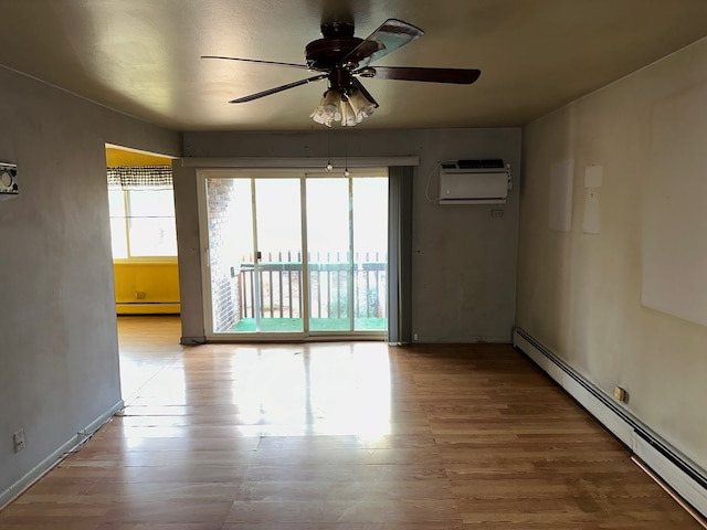 spare room featuring light hardwood / wood-style flooring, a wall mounted AC, a baseboard radiator, and ceiling fan