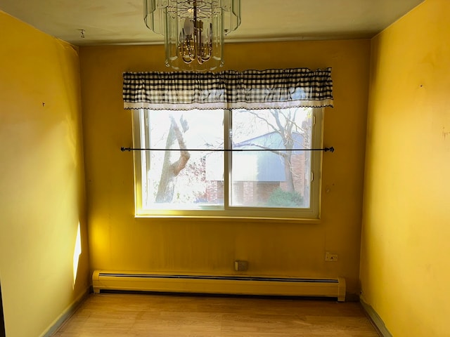 unfurnished dining area with a baseboard heating unit, wood-type flooring, and a wealth of natural light