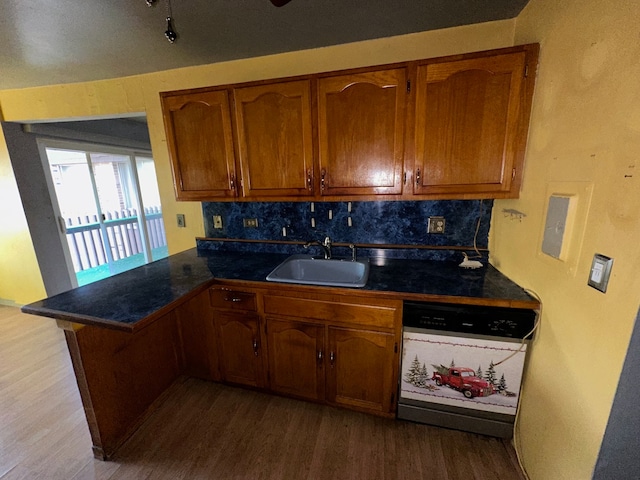 kitchen featuring white dishwasher, sink, kitchen peninsula, and hardwood / wood-style flooring