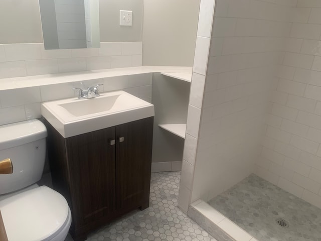 bathroom with vanity, toilet, a tile shower, and tile patterned flooring