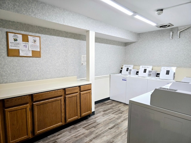 laundry area with cabinets, light hardwood / wood-style flooring, and washing machine and dryer