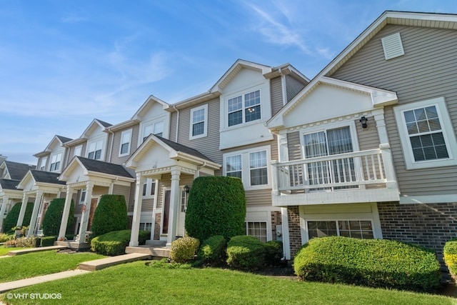 view of property featuring a front yard and a balcony