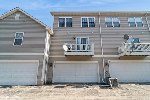 back of house with a balcony, central AC unit, and a garage