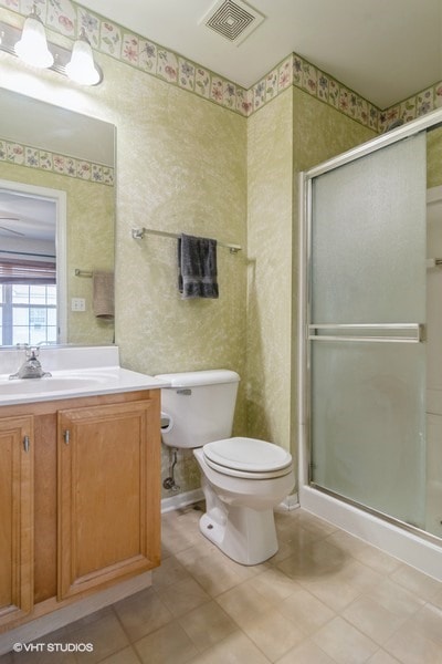 bathroom featuring vanity, toilet, walk in shower, and tile patterned flooring