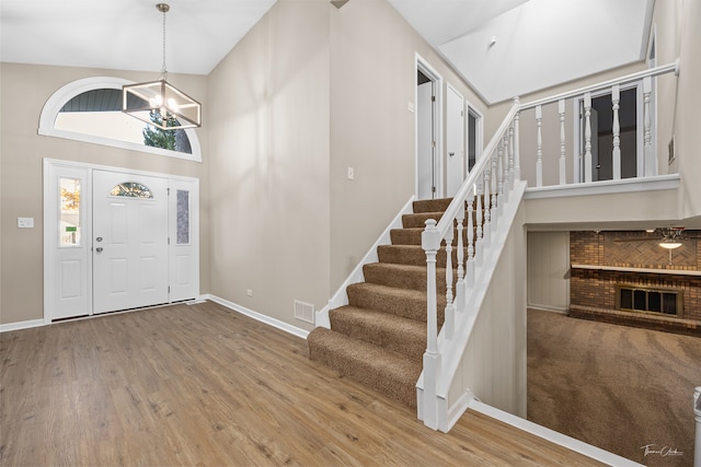 entrance foyer featuring an inviting chandelier, hardwood / wood-style flooring, and high vaulted ceiling