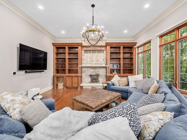 living room with a stone fireplace, wood-type flooring, ornamental molding, and a chandelier