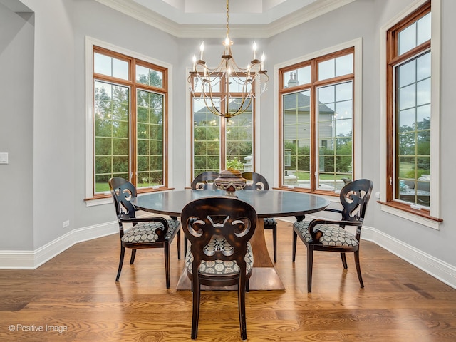 dining area featuring an inviting chandelier, ornamental molding, wood-type flooring, and a healthy amount of sunlight