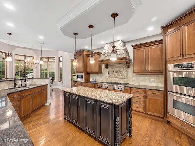 kitchen featuring dark stone countertops, wood-type flooring, appliances with stainless steel finishes, and pendant lighting