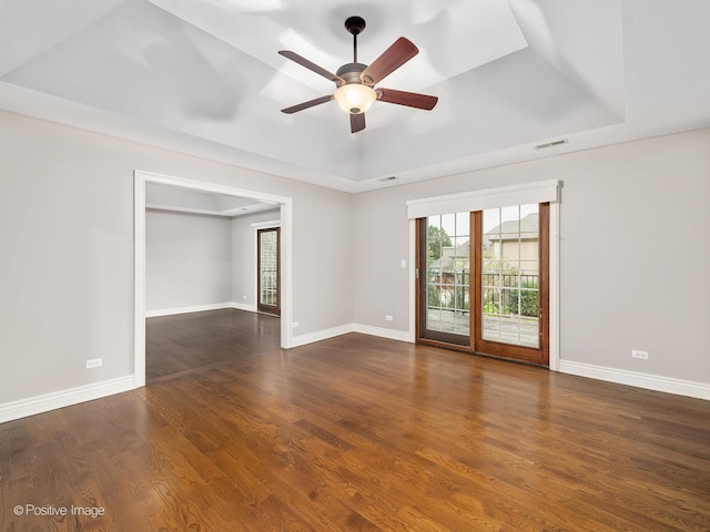 spare room with dark hardwood / wood-style floors, a raised ceiling, and ceiling fan