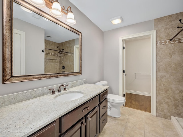 bathroom featuring vanity, toilet, tiled shower, and tile patterned flooring