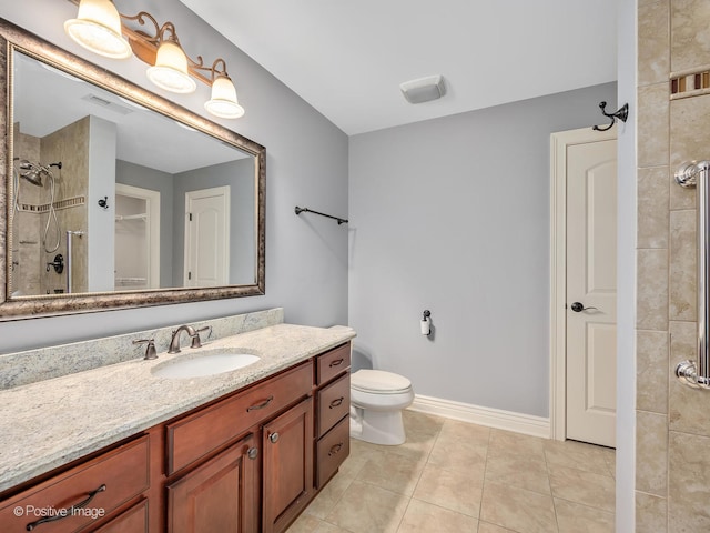 bathroom with vanity, tiled shower, toilet, and tile patterned flooring