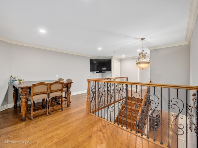 hall with light hardwood / wood-style flooring, a notable chandelier, and crown molding