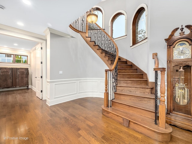 stairs with ornamental molding and hardwood / wood-style floors