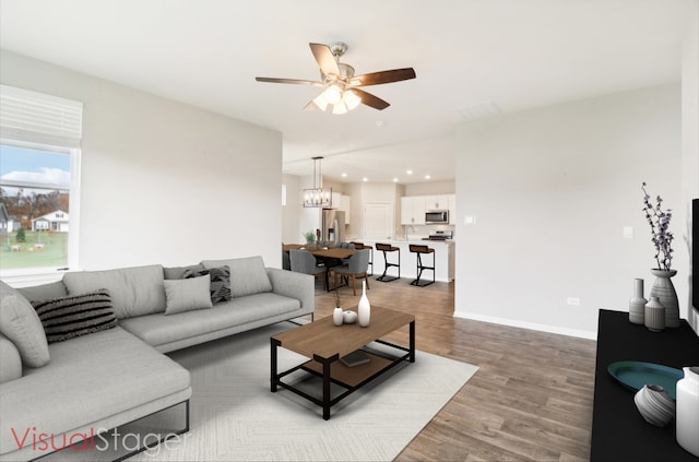 living room with wood-type flooring and ceiling fan with notable chandelier