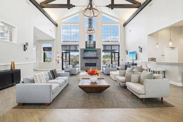 living room featuring beam ceiling, hardwood / wood-style floors, a chandelier, and high vaulted ceiling