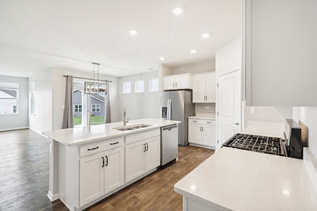 kitchen featuring a kitchen island with sink, dark hardwood / wood-style floors, stainless steel appliances, decorative light fixtures, and white cabinetry