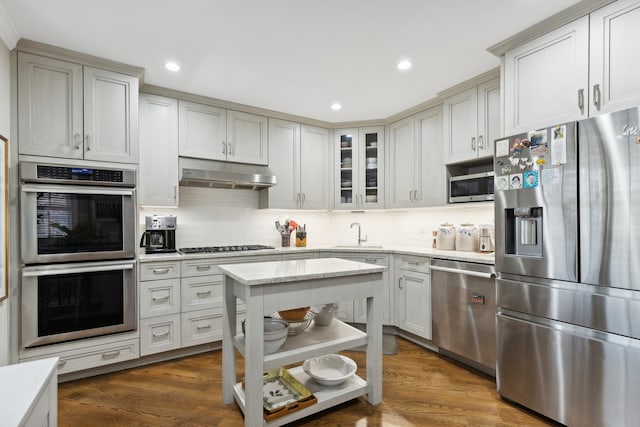 kitchen with tasteful backsplash, light stone countertops, appliances with stainless steel finishes, sink, and dark hardwood / wood-style floors