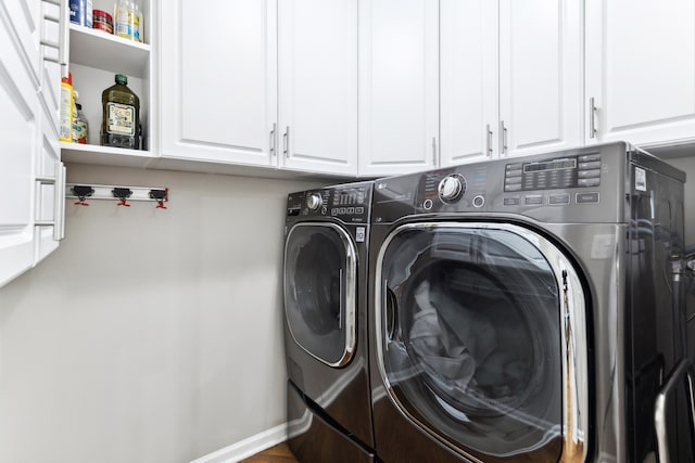 clothes washing area with washing machine and dryer and cabinets