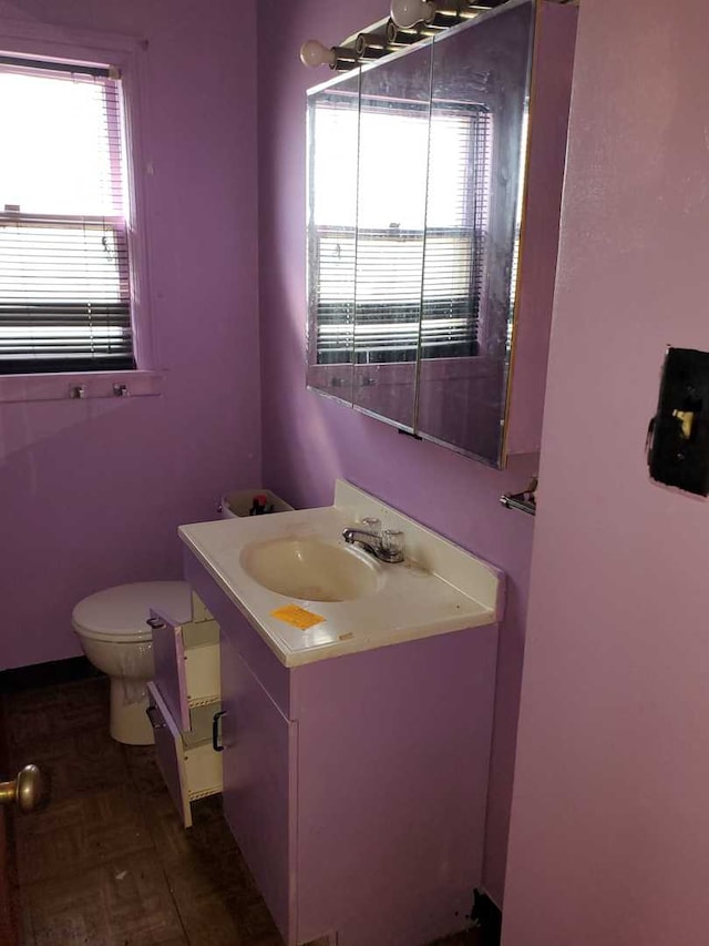 bathroom featuring parquet flooring, vanity, and toilet