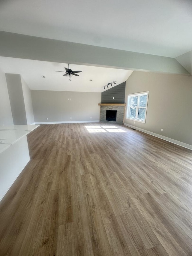 unfurnished living room with ceiling fan, vaulted ceiling, and light wood-type flooring